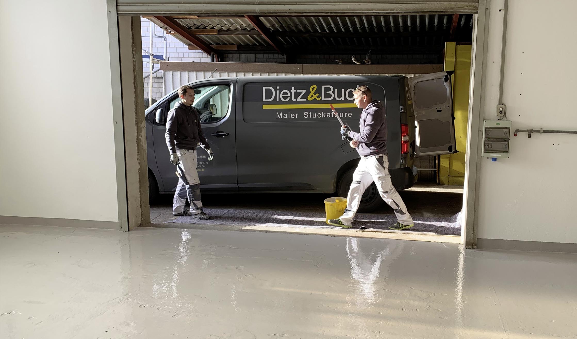 Foto von Malern von Dietz und Buck, die auf einer Baustelle vor dem Firmenwagen laufen