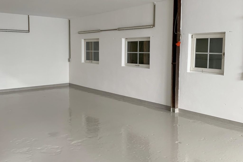 Bild von einer Garage mit weißen Wänden und einem grauen Garagesiegel nach einer Renovierung.