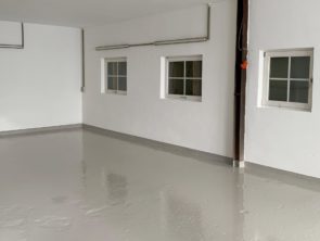 Bild von einer Garage mit weißen Wänden und einem grauen Garagesiegel nach einer Renovierung.