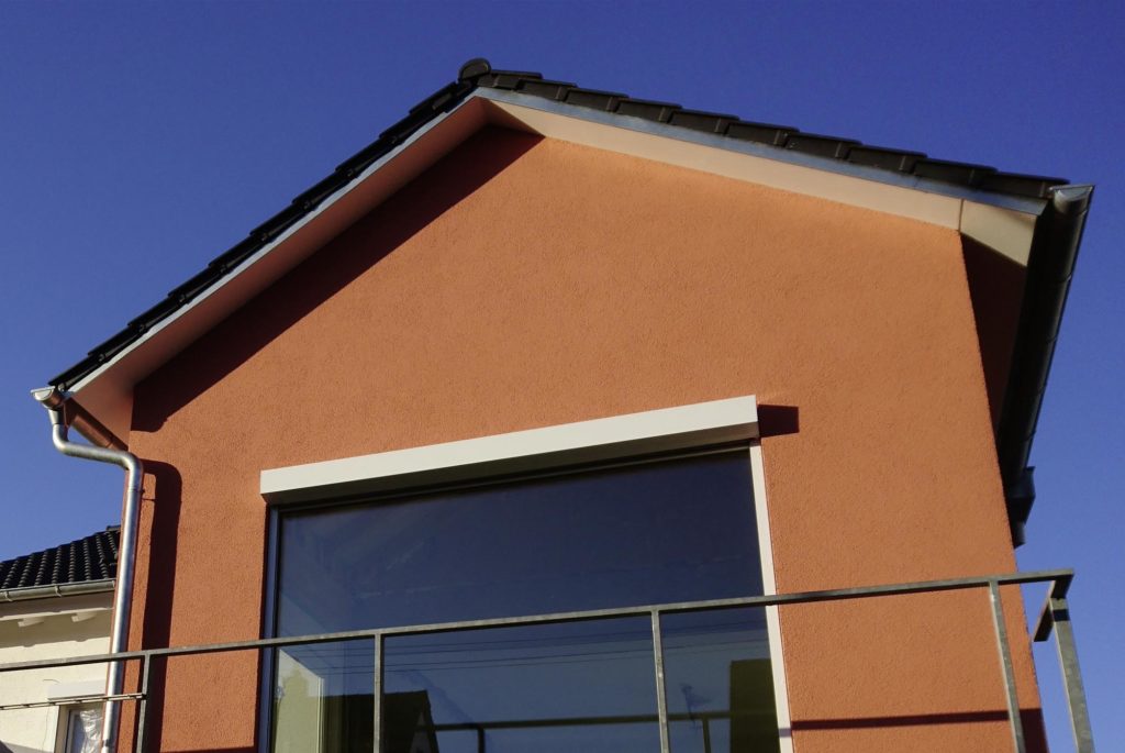 Fassade eines Hausanbaus mit orangenem Anstrich