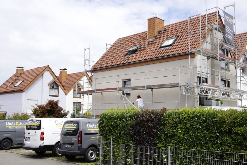 Reihenhaus hinter Hecke mit Gerüst und beigem Fassadenanstich von Dietz und Buck