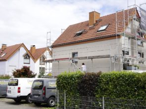 Reihenhaus hinter Hecke mit Gerüst und beigem Fassadenanstich von Dietz und Buck